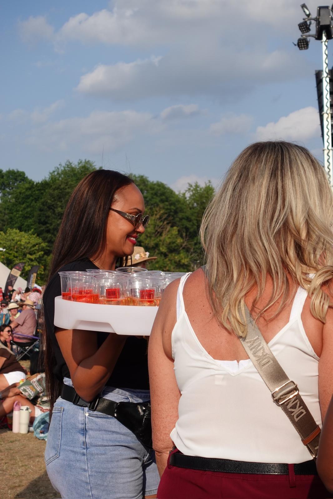 Reign shot seller serving a festival guest in the sun