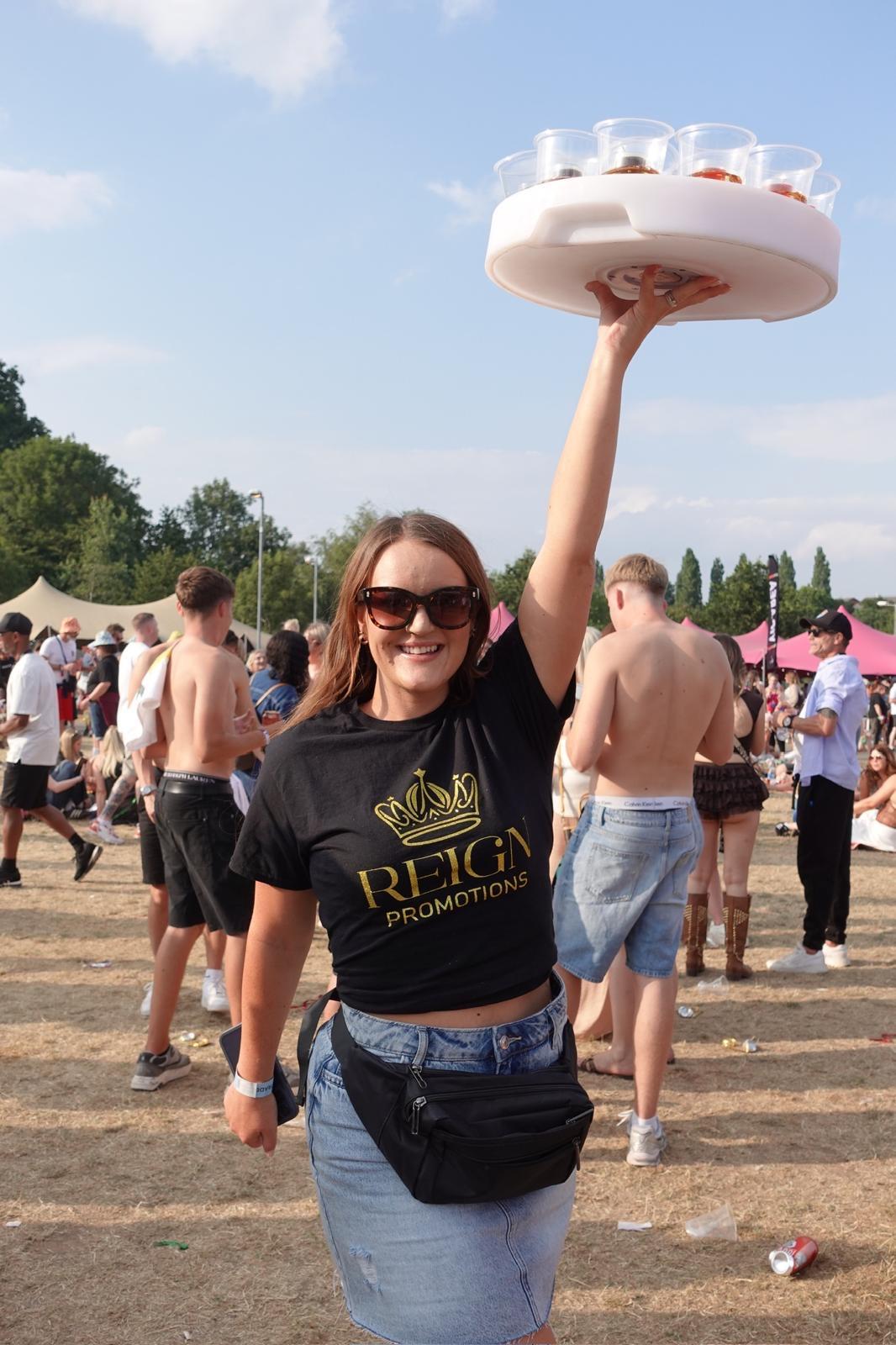 Reign shot seller holding illuminated tray high at a festival