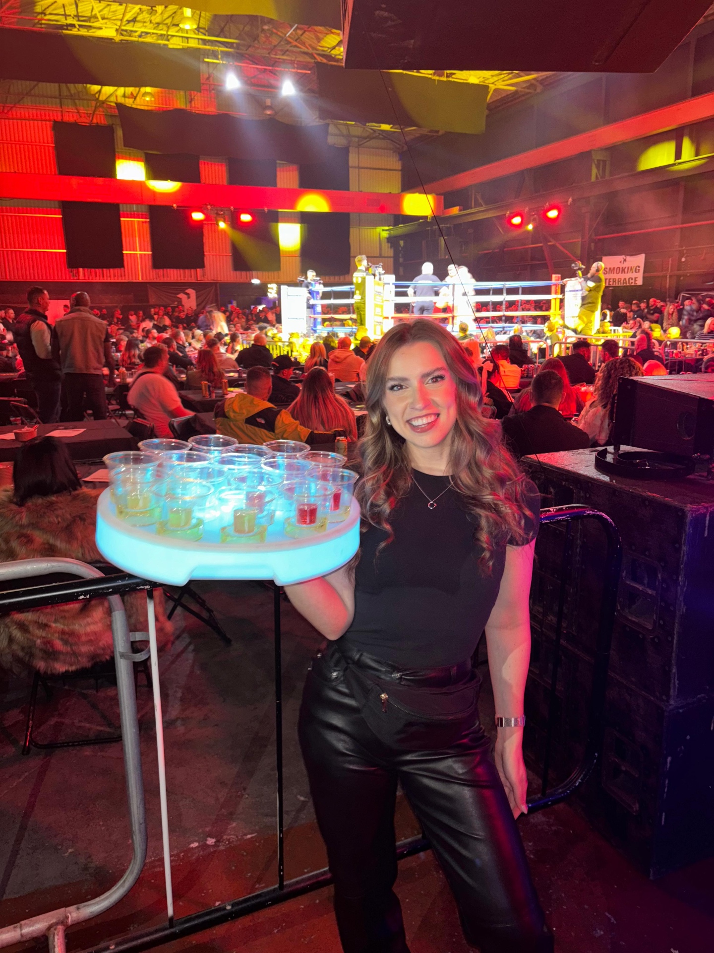 Reign shot seller with glowing tray at a boxing event