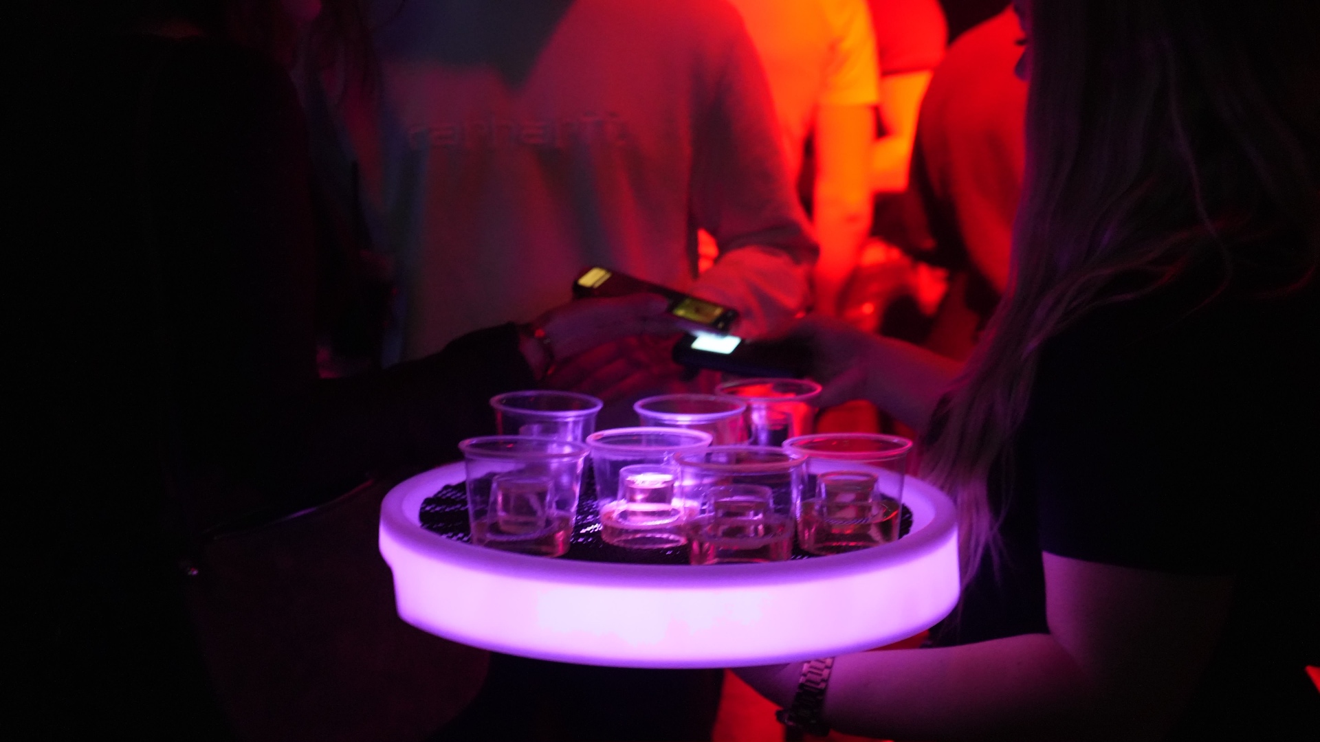 Reign shot seller with an illuminated tray in red club lighting