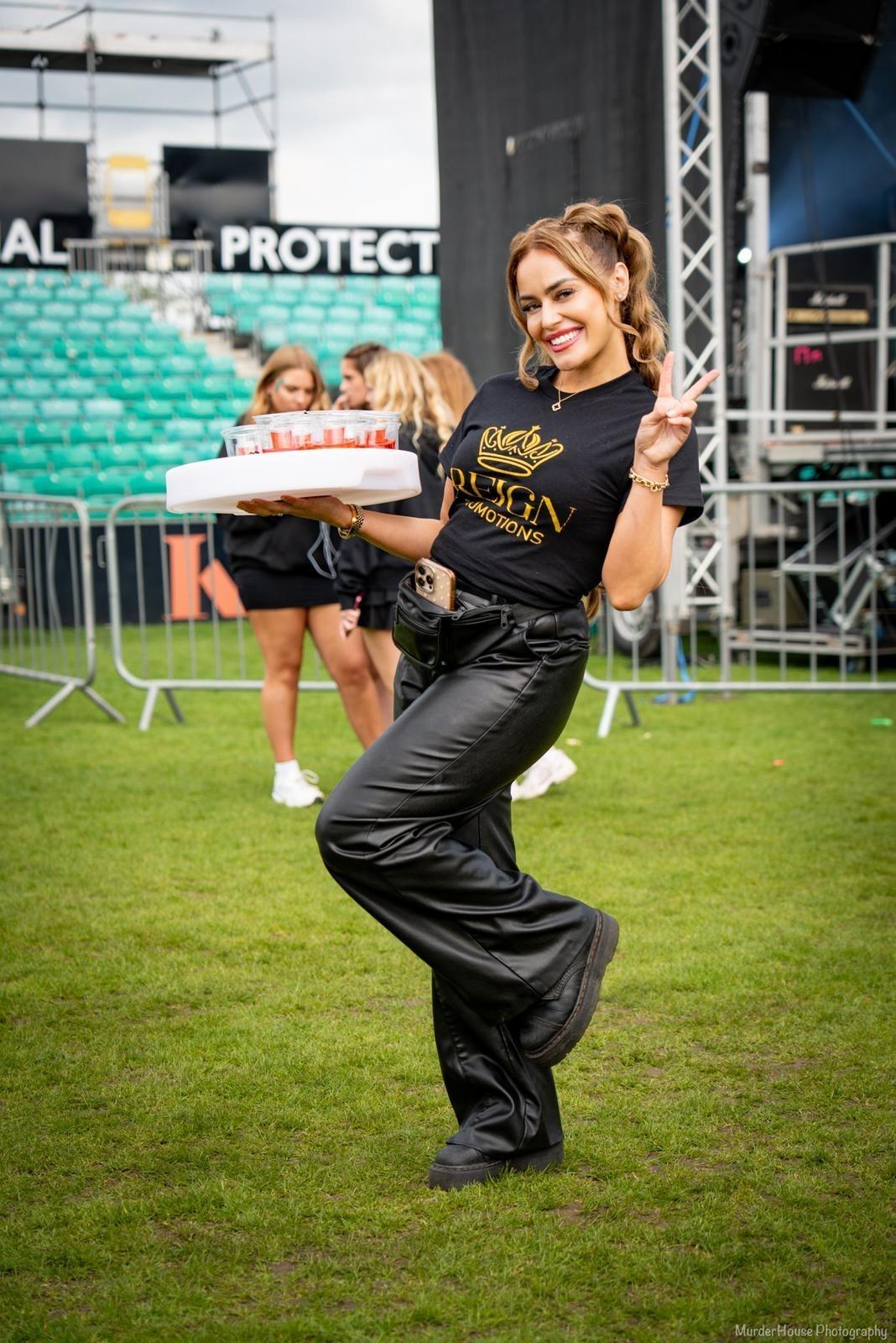 Reign shot seller posing with tray at a festival