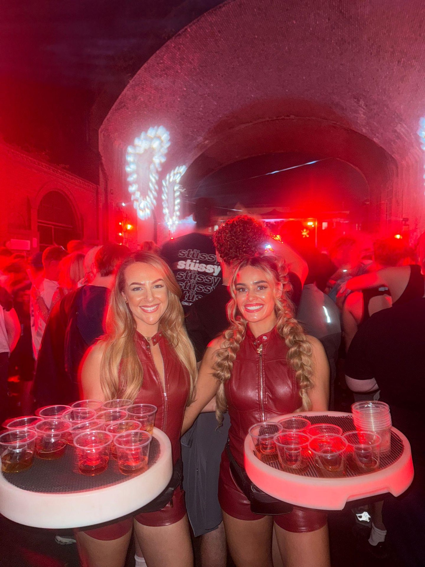 Reign shot sellers in red latex outfits at a warehouse event