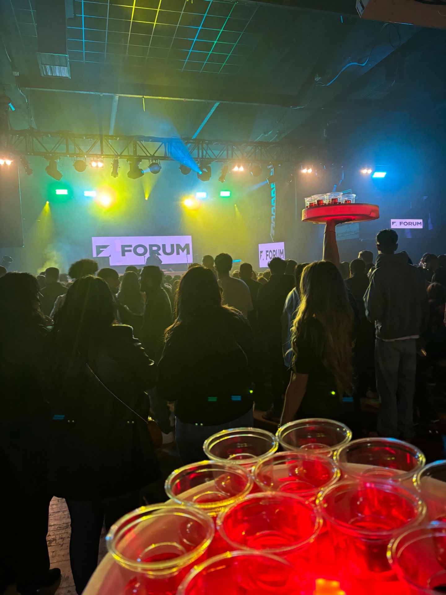 Reign shot trays raised over the crowd at Forum